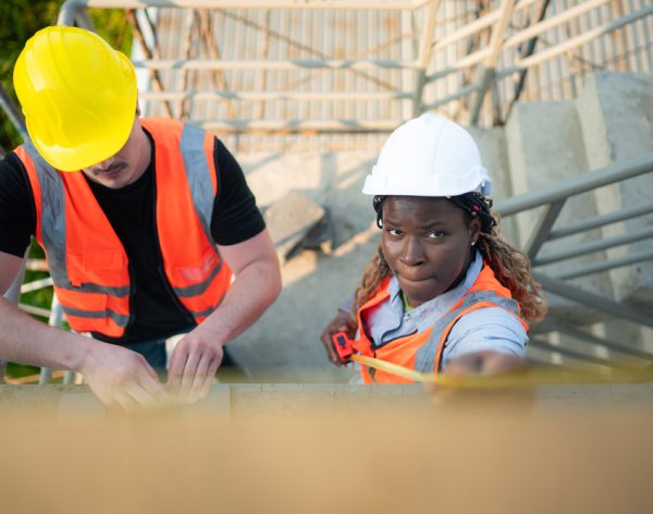 Male and female engineers working on construction site, They are inspecting the cement plaster work on the walls and balconies of the building.